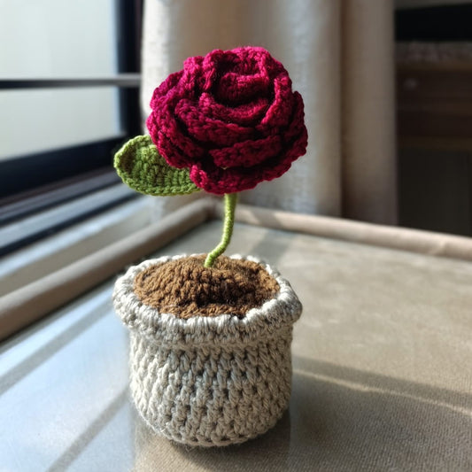 Close-up of handmade crochet flowers in a decorative yarn flower pot