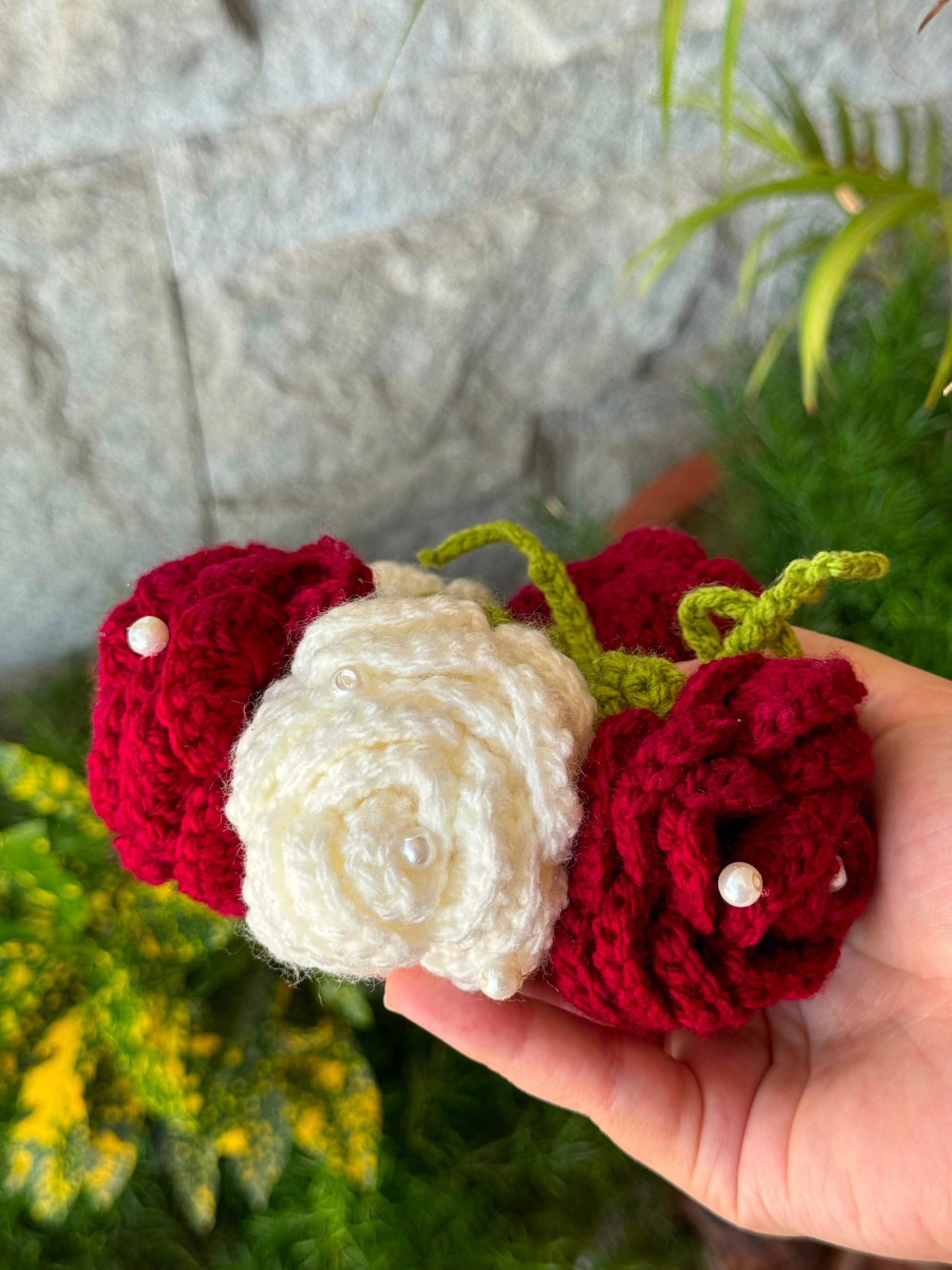 Close-up of handmade crochet flower gajra with maroon and ivory roses